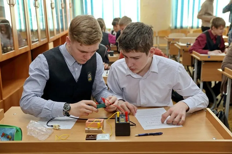 Doi elevi montează împreună un circuit electric în timpul unei lucrări de laborator