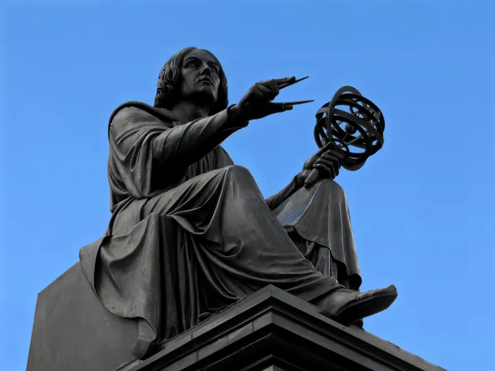 Statuia lui Nicolaus Copernic ținând o sferă armilară, pe cer senin