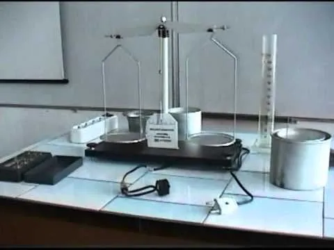 Balanță de laborator cu talere, alături de cilindri gradați, pe masa de lucru